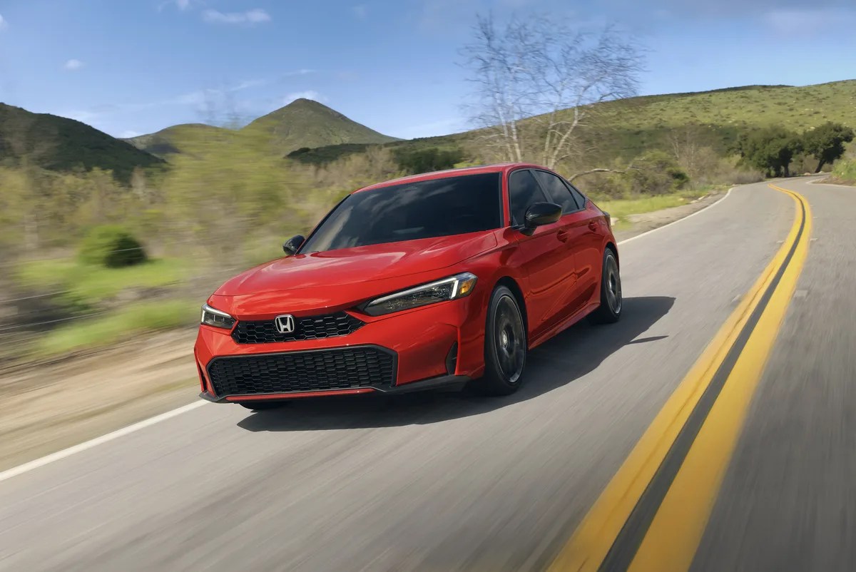 red honda civic drives down a road