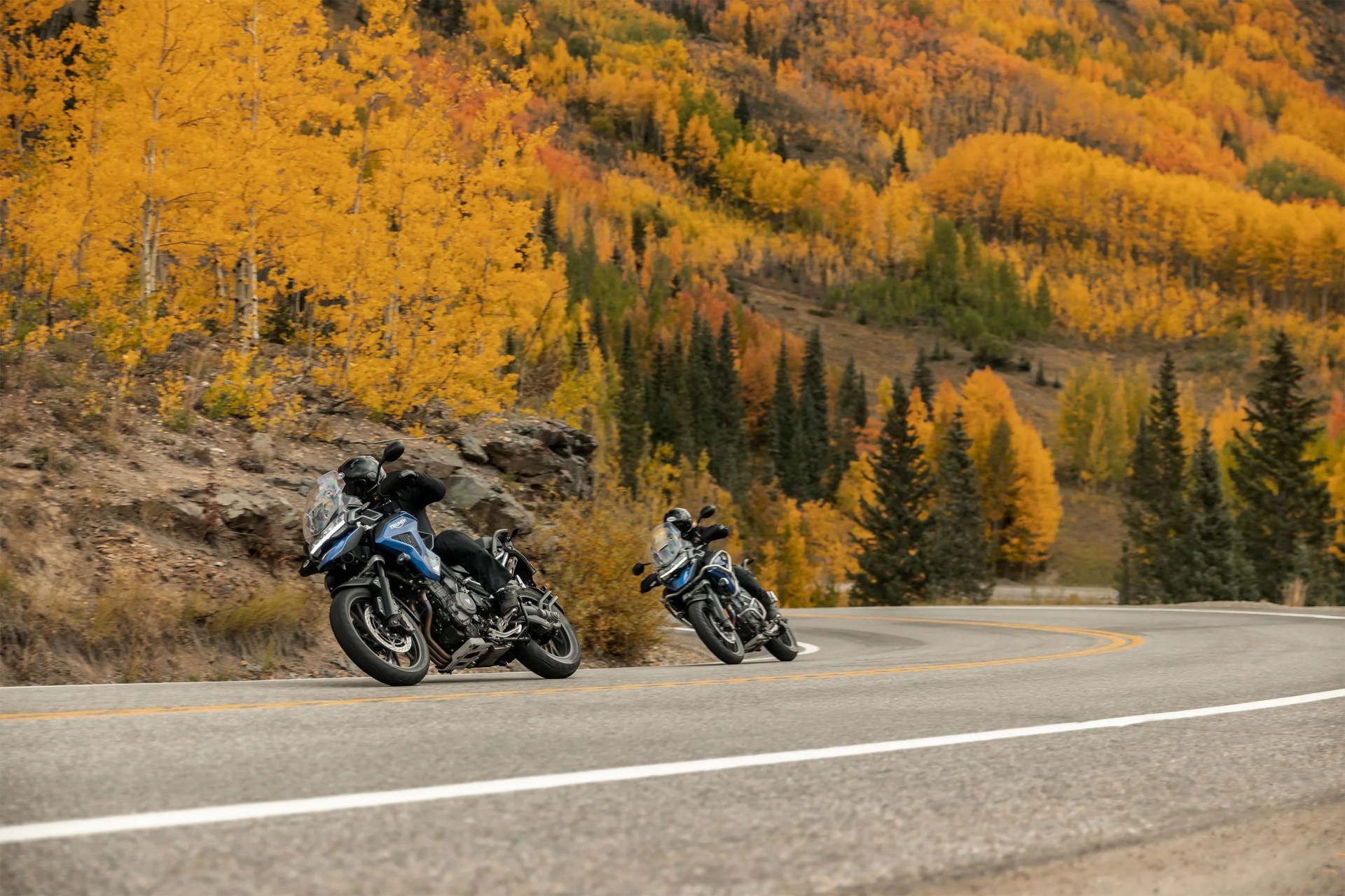 two people riding motorcycles on a curvy road