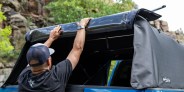 man accessing truck bed through an open soft truck topper panel