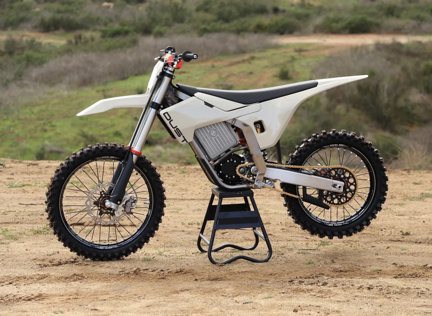 Dust Moto Model 1 Electric Dirt bike sitting on stand on dusty road