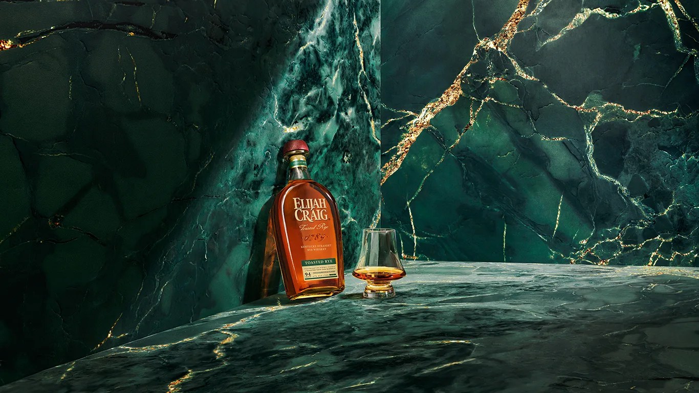 elijah craig whiskey bottle and glass in a green stone room