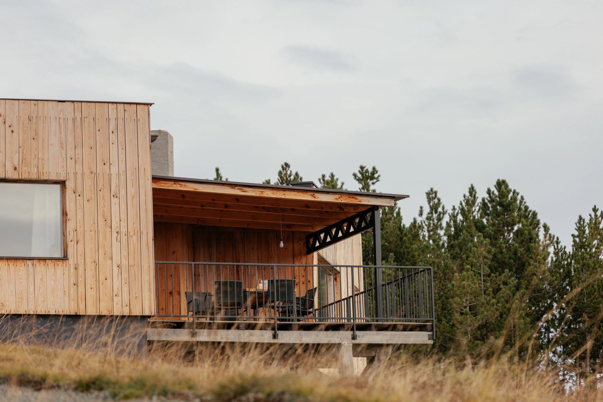 A modern mountain cabin with a deck with a table and chairs.