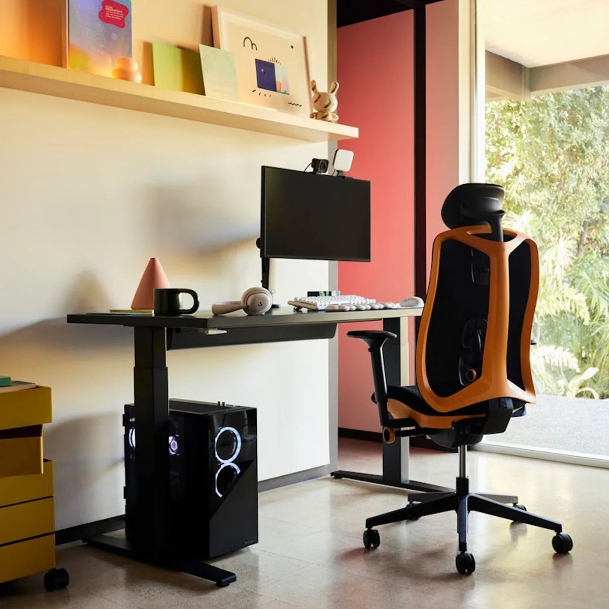 Herman Miller Vantum gaming chair in Helios Orange show positioned next to a computer desk with a gaming monitor and PC tower underneath in a modern looking room highlighted by a floor to ceiling window letting in natural light.