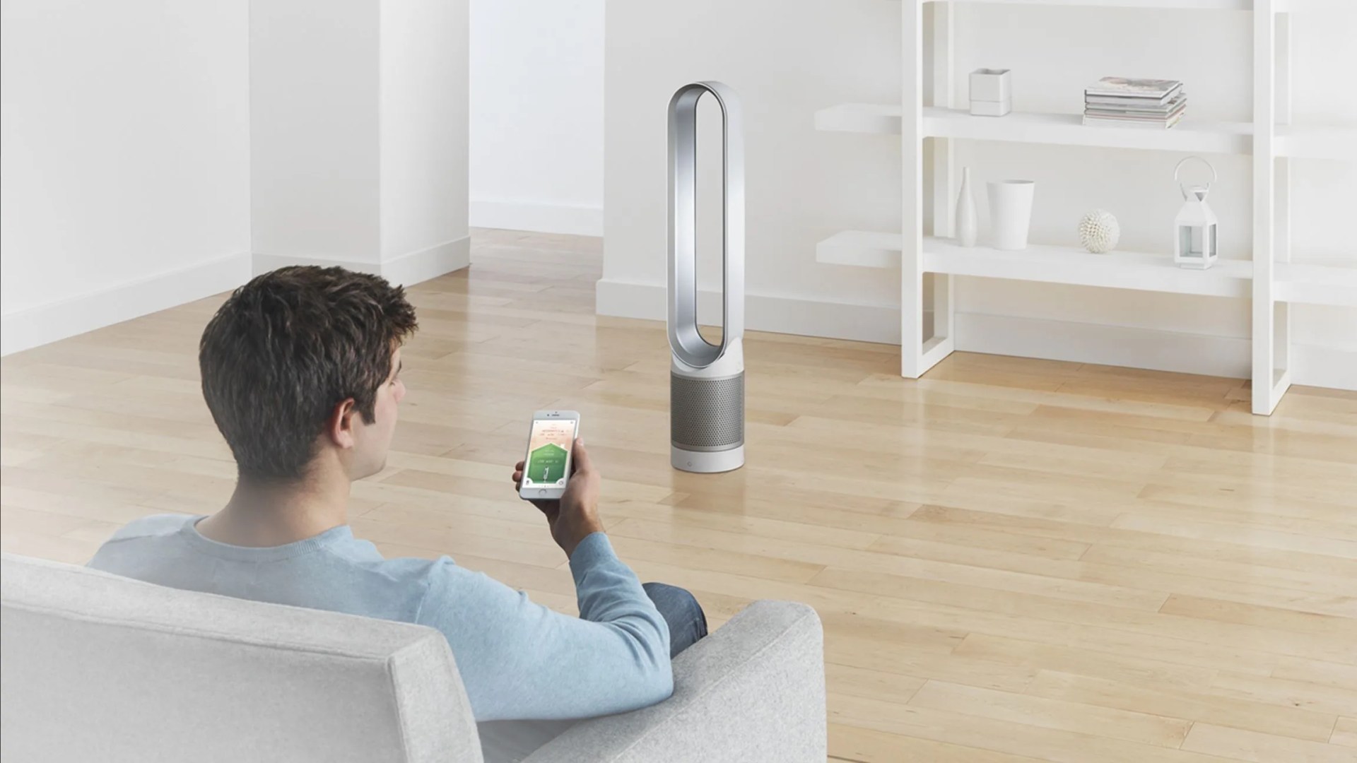 a man sitting on a couch on his phone with an air purifier in the room