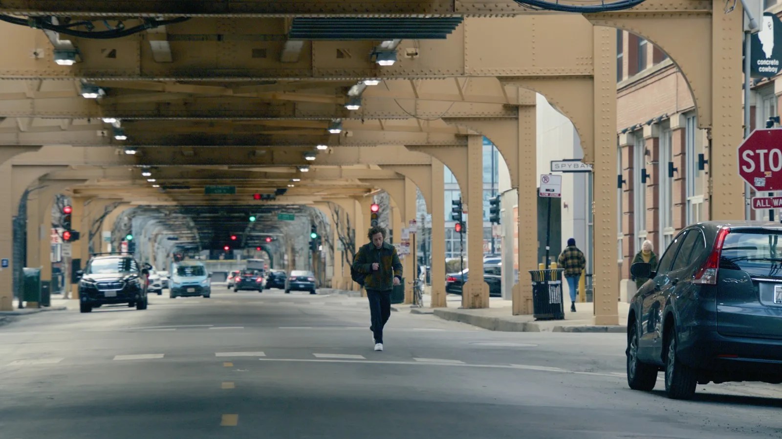 man walking under bridge