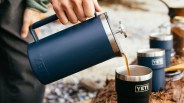 Yeti Rambler french press pouring coffee into Yeti rambler mugs in an outdoor setting