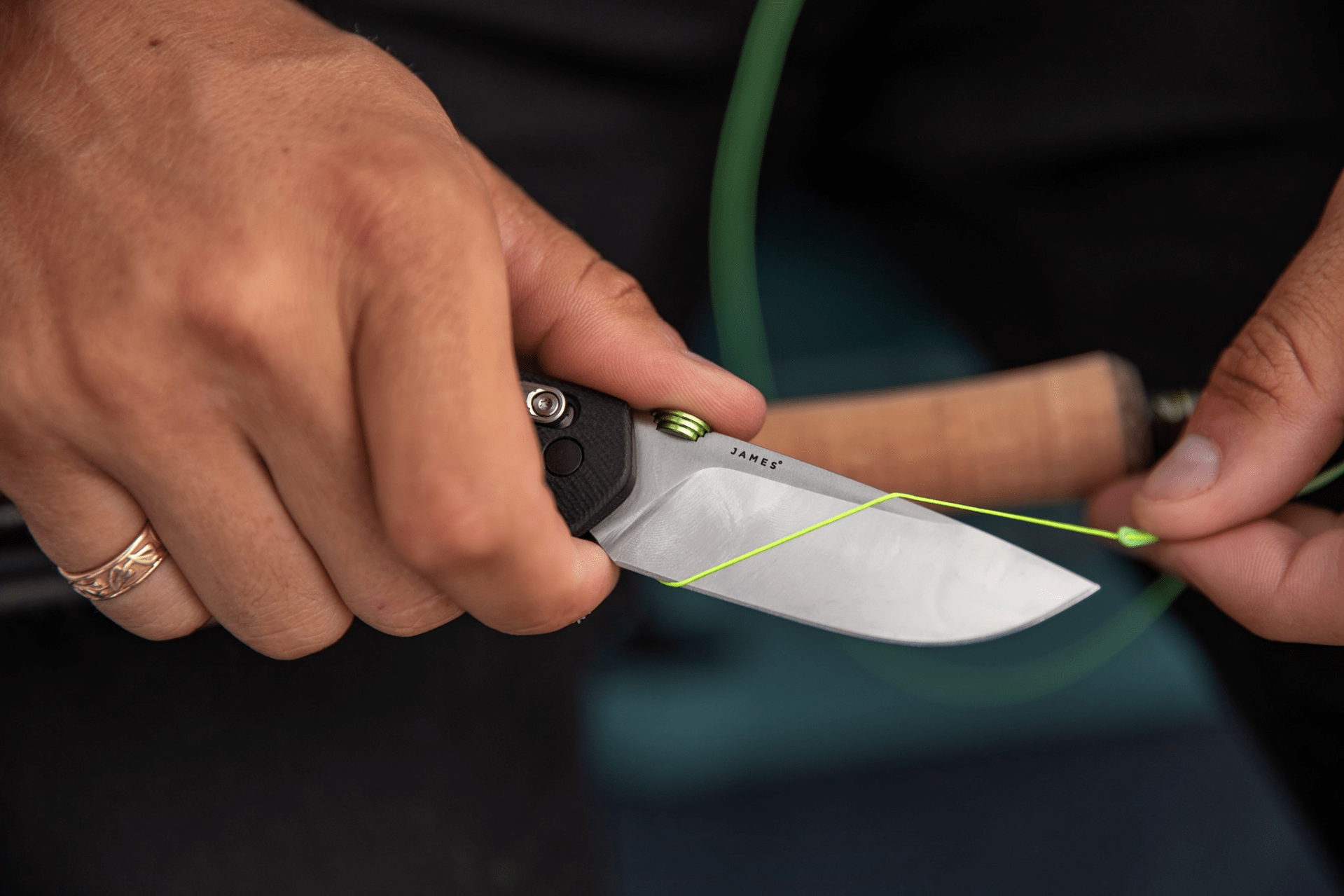 Close up of a person using a James Brand knife to cut fishing line